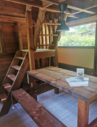 Vue intérieure de la tente lodge avec table de pique-nique, en location au camping **** du Lac Cormoranche dans l'Ain